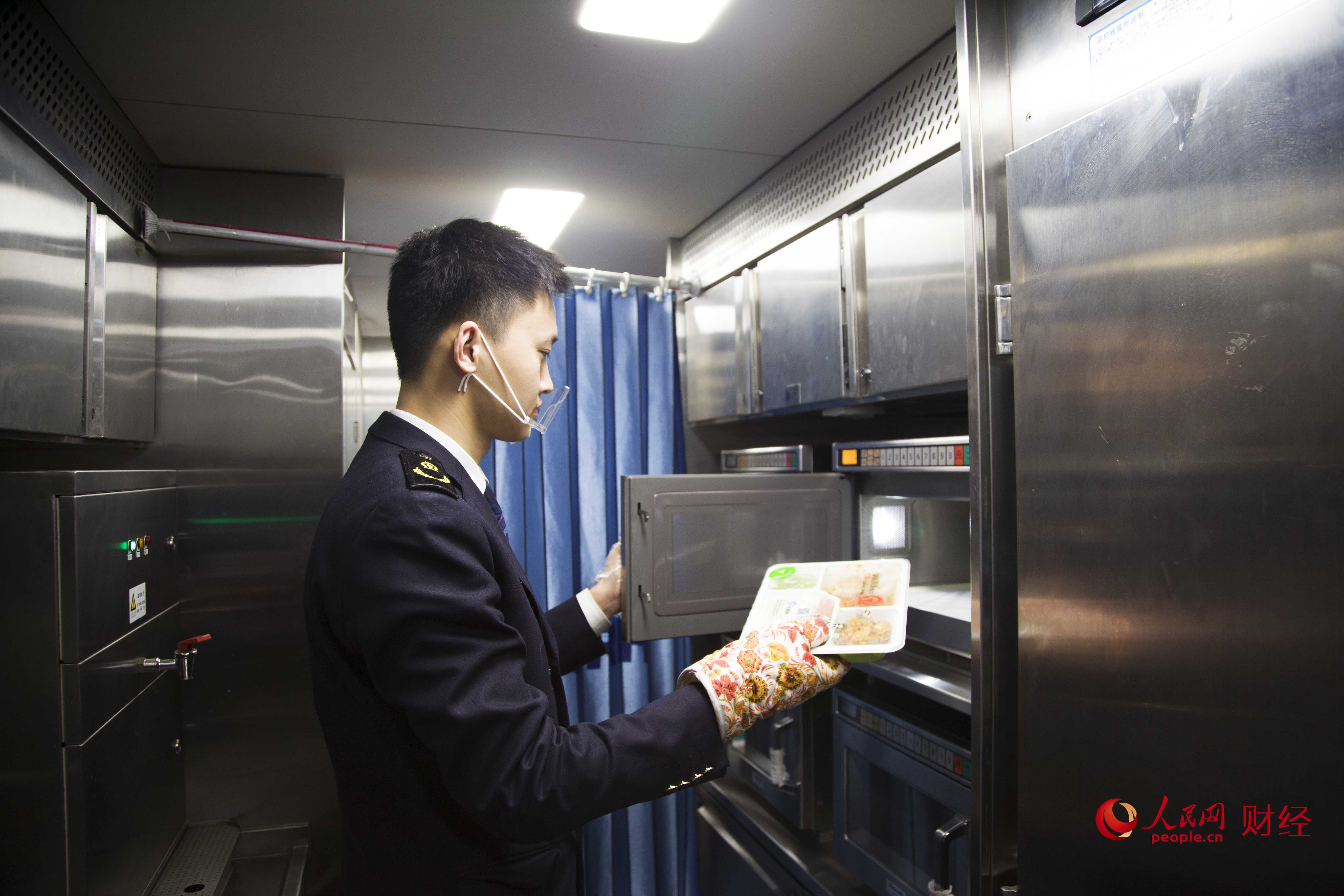 G308列車上，餐車服務員正在加熱盒飯，他每天平均要加熱180多份盒飯。