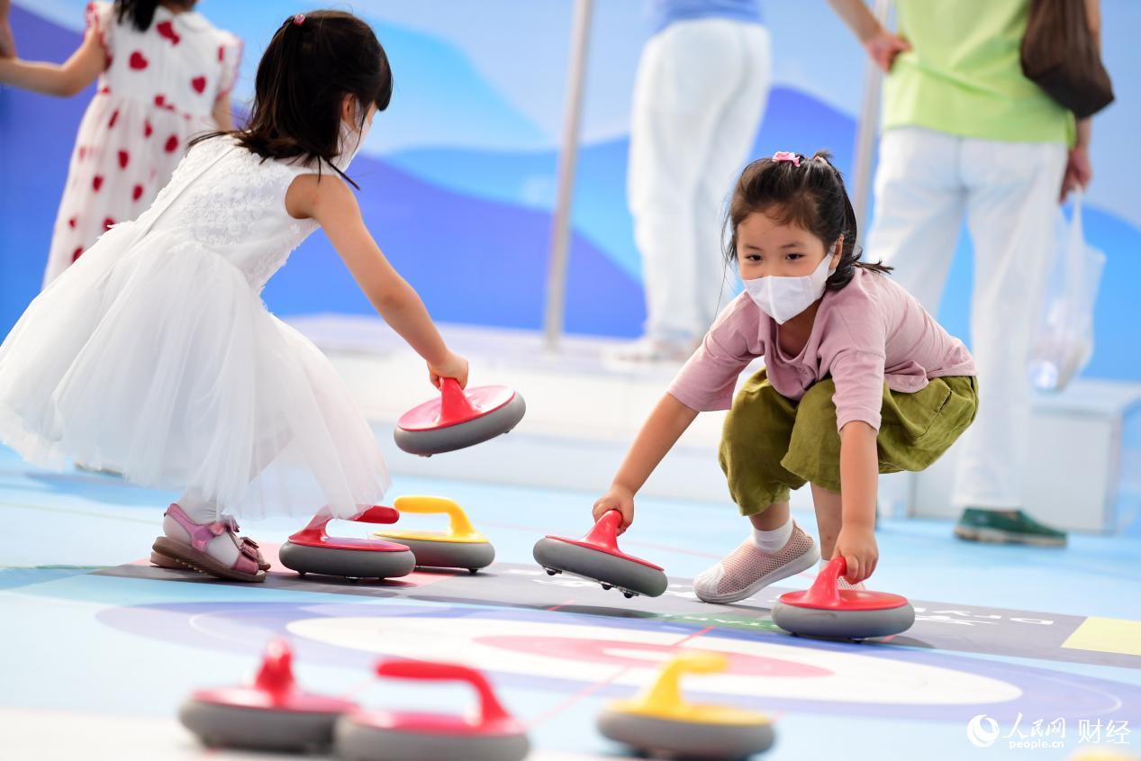 在冬季運動展區，孩子們正在體驗旱地冰壺樂趣。（人民網記者 於凱 攝）