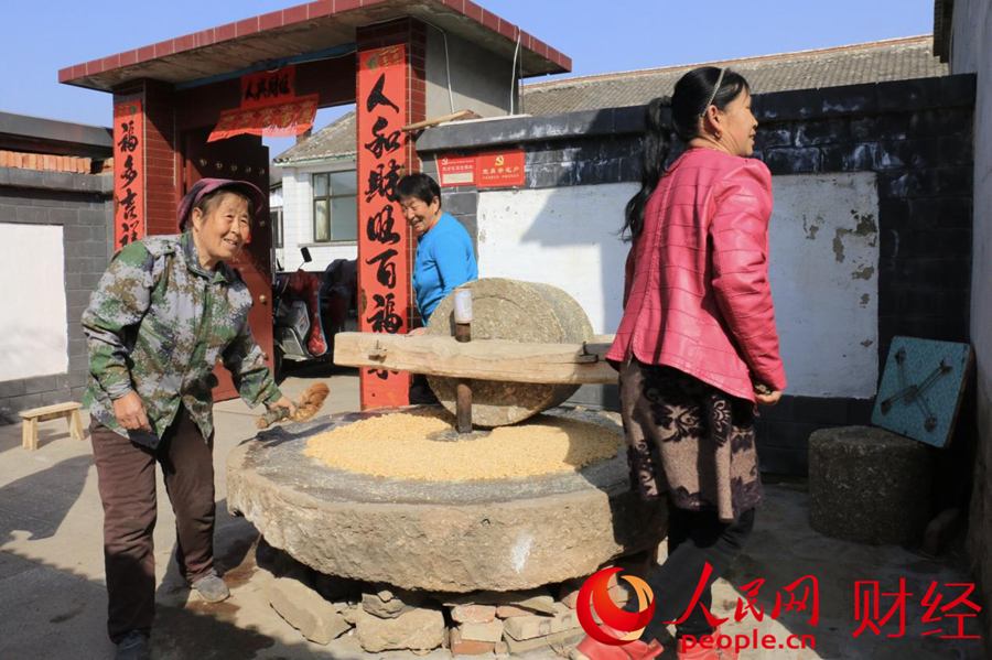 在平坊滿族鄉於營村，三戶村民合力推碾，將去年豐收的玉米擀出香甜的面粉。人民網 黃盛攝