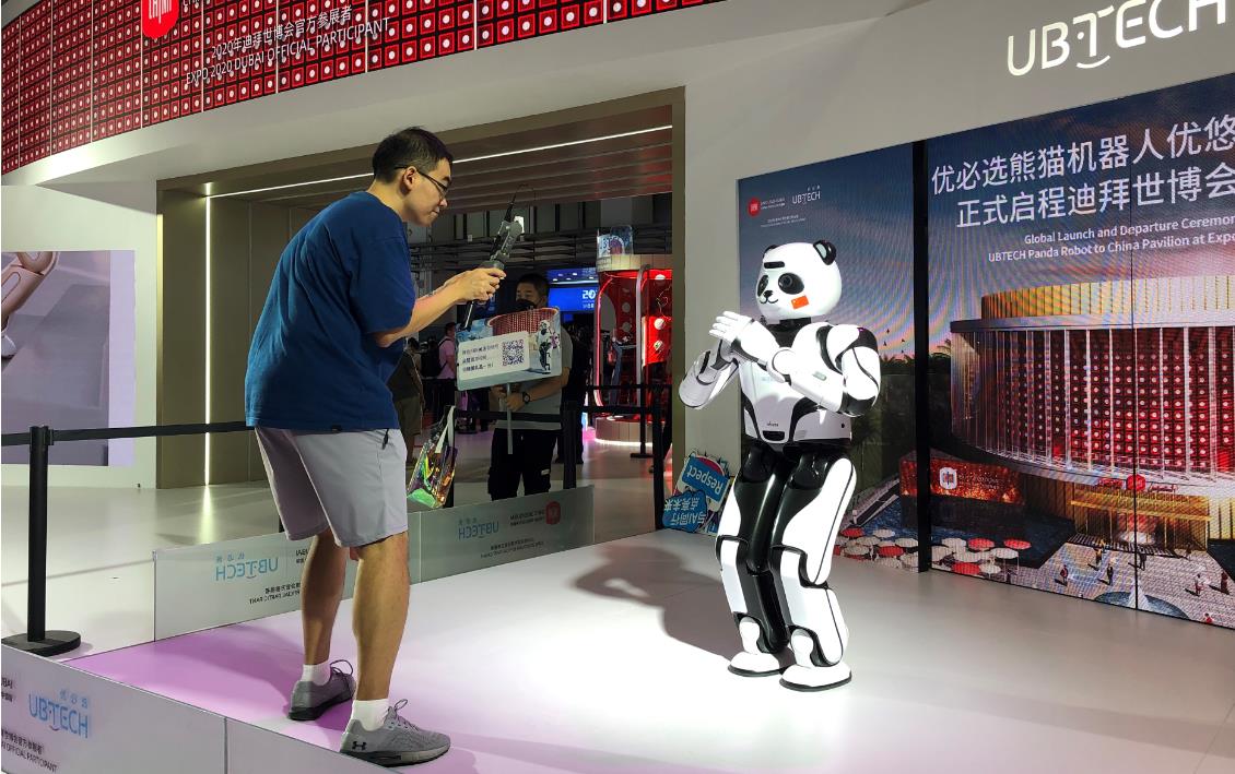 一位观众正在与能够双腿行走的熊猫机器人互动。人民网记者 王震慑