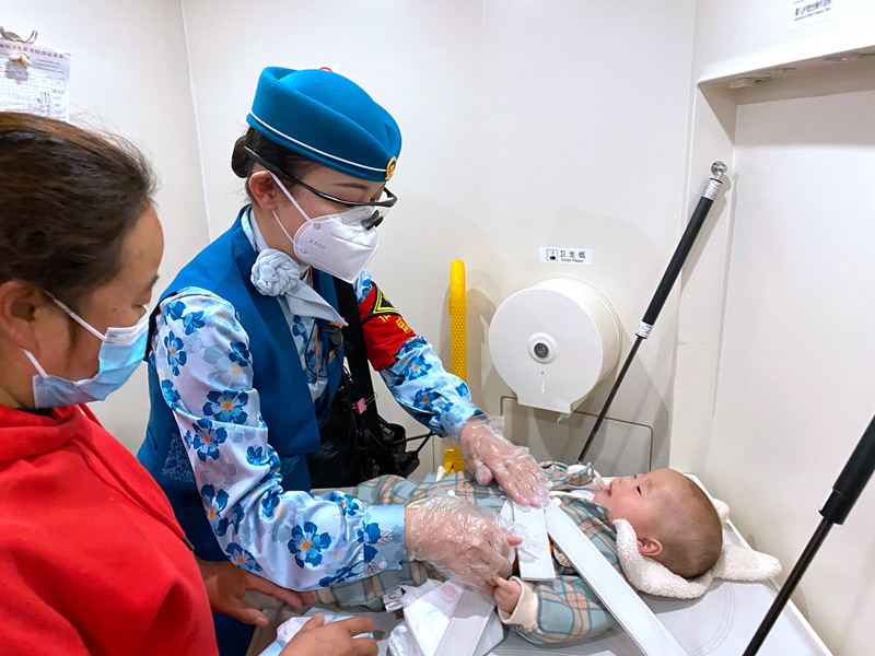 昆明客運段中老鐵路列車長趙瑩靜幫助旅客為嬰兒更換尿布。全國鐵道團委供圖