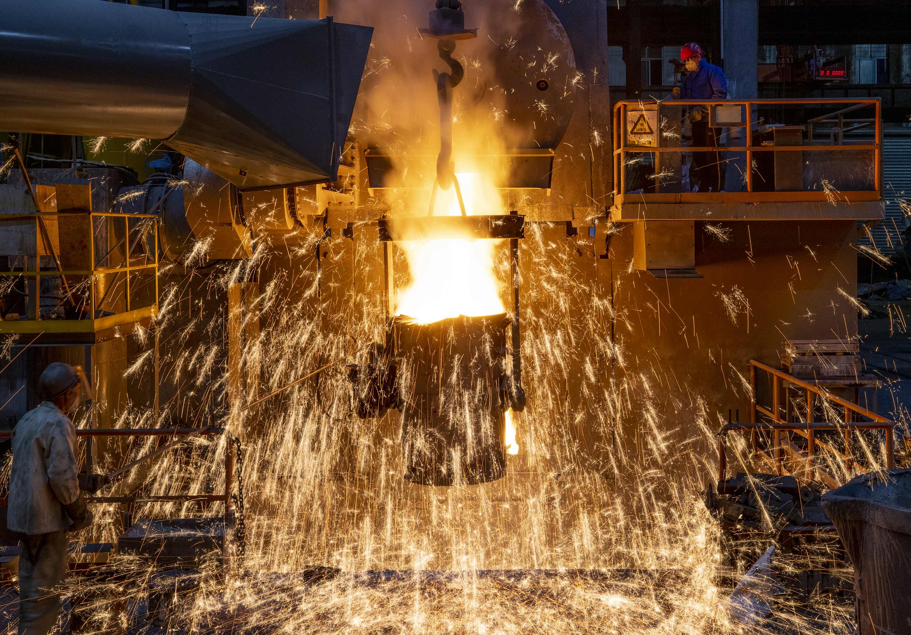浙江一家机铸企业工人在数字化车间操作，把电炉内的铁水倒入浇铸包。图片来源：人民图片