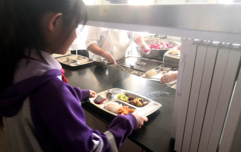 伊金霍洛旗第一小学学生正在打饭，今天的饭菜是三菜一汤外加水果，学生可以多次盛取，吃饱为止。人民网记者 孙博洋摄