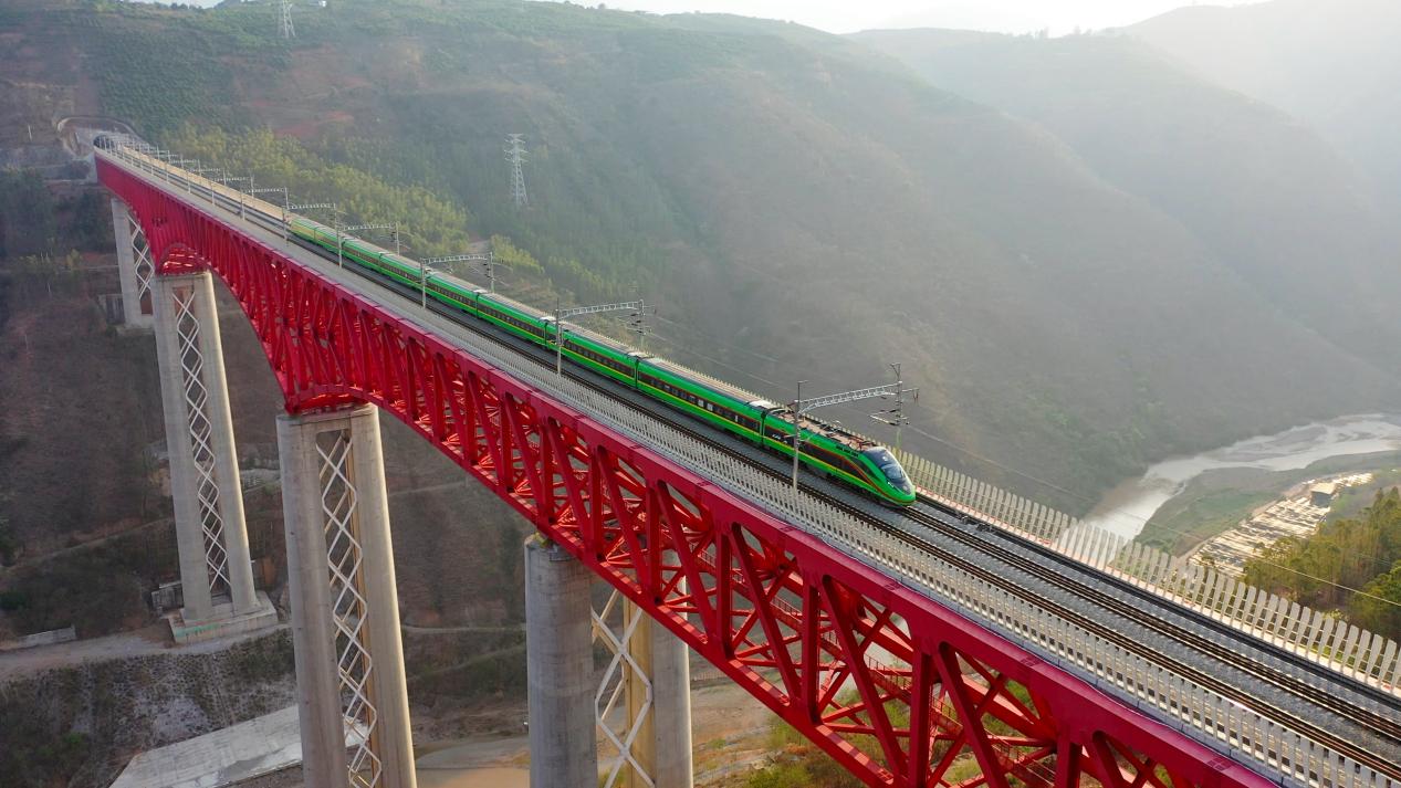 中老铁路国际搭客列车在云南省境内的元江特大桥上奔突。姚巍摄