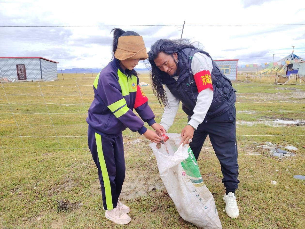 玉树州称多县珍秦镇河湖志愿者才培和他女儿更求拉毛在清扫垃圾。受访者供图