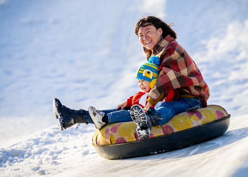家长陪伴孩子在呼和浩特市玉泉区大库伦村“冰雪大世界”内玩雪圈	。提供了更多新玩法，丁根厚摄