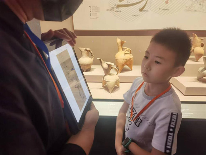 在山东博物馆，前来参观的小朋友正认真听工作人员讲解。人民网记者 杨迪摄