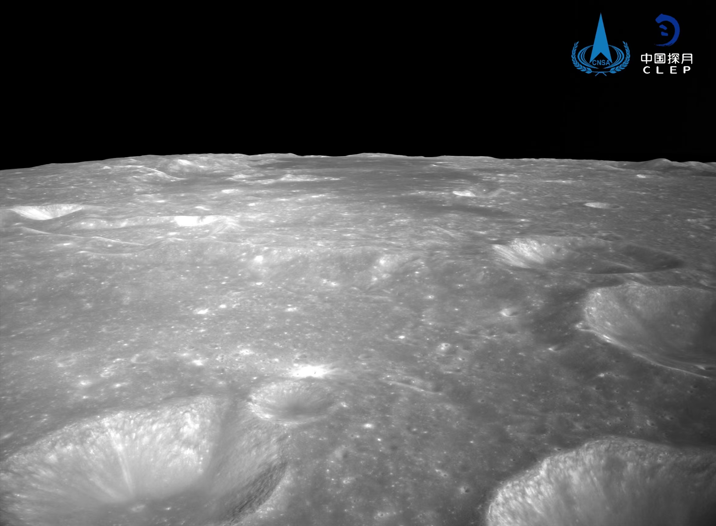 该图由降落相机刚开机时拍摄，图像显示拍摄月背区域中下部和右部分布有多个十多公里直径的环形坑，拍摄的月背区域上部中间为暗色的玄武岩分布区。