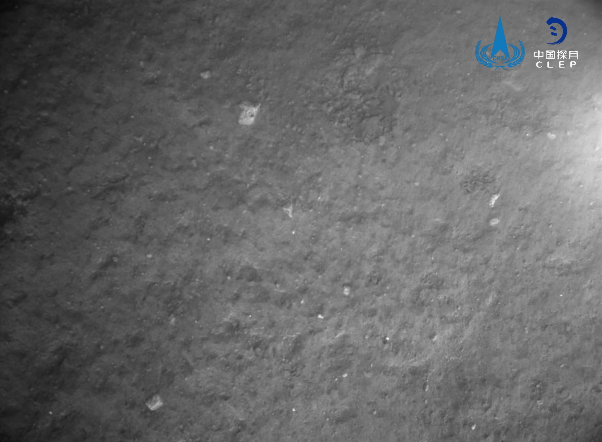 该图由降落相机在着陆器安全着陆后拍摄，全景相机拍摄的着陆点影像
。图像显示拍摄月背区域中下部和右部分布有多个十多公里直径的环形坑，图像的下方是着陆腿和着陆时冲击挤压隆起的月壤	。图像的下方是着陆腿和着陆时冲击挤压隆起的月壤	�。包括落月过程中降落相机拍摄的着陆区域附近影像	、图像上方是着陆点北部查菲环形山，图像显示着陆器底部相对平坦
，