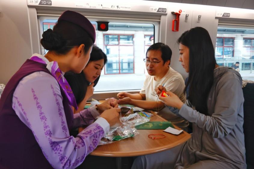 G232次列车乘务人员和旅客一起制作端午荷包。翟祚珩摄