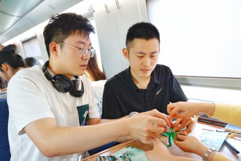 G232次旅客亲手制作端午荷包和五彩绳。王磊摄