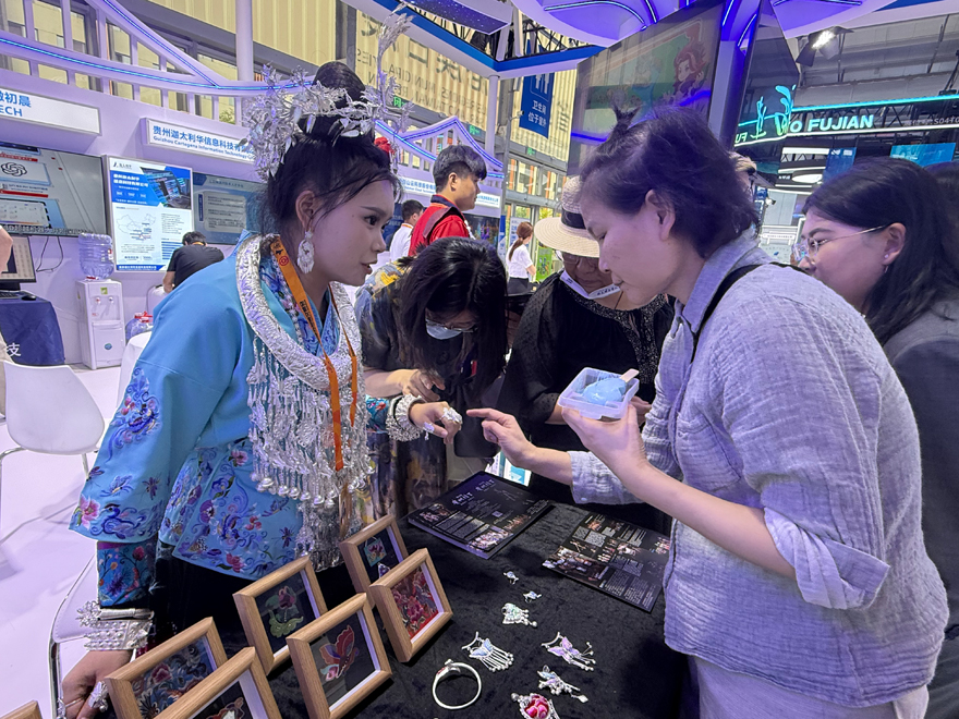 貴州展台工作人員向觀眾介紹苗繡和銀飾等展品。人民網記者 杜燕飛攝