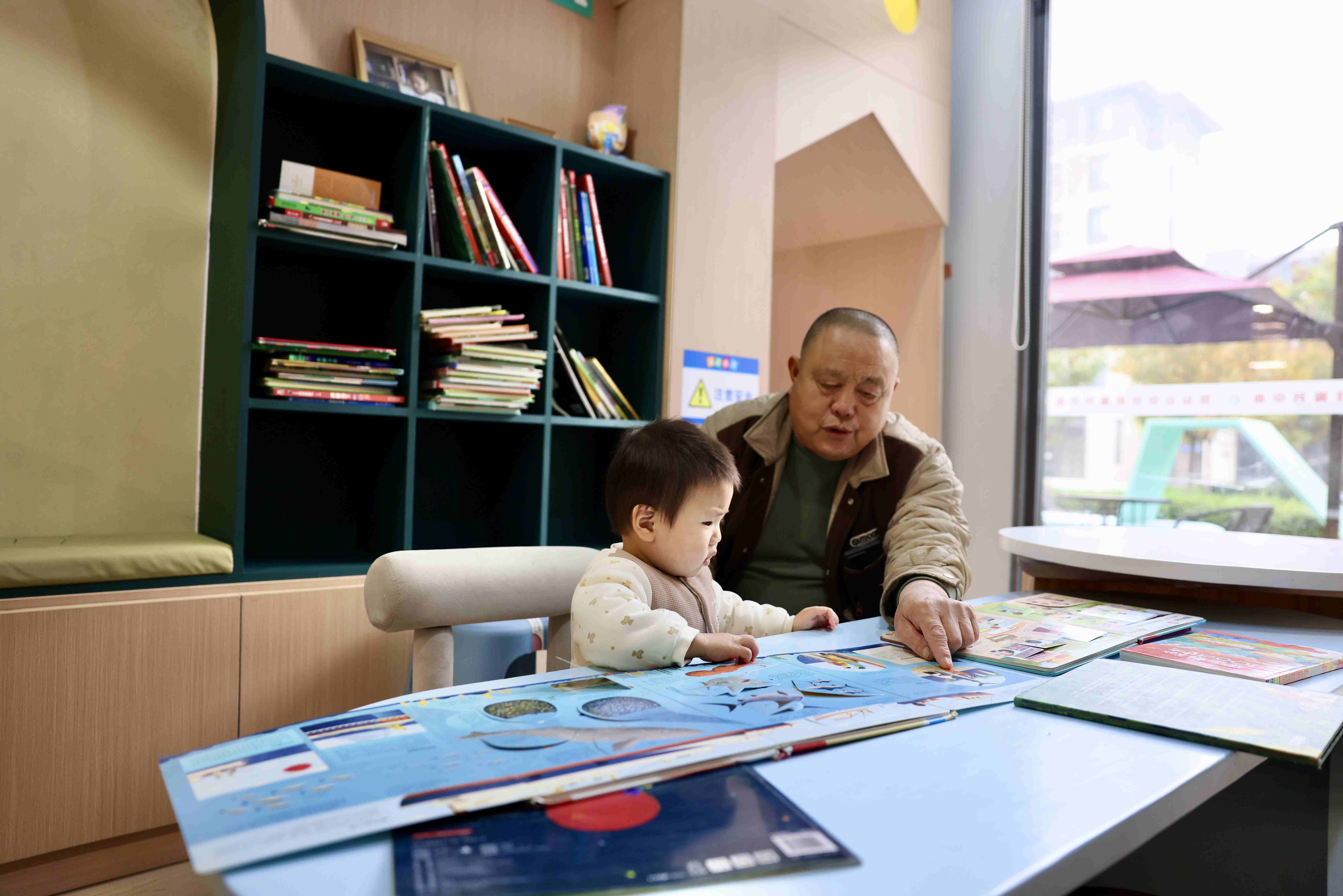 当地居民“一老一小”在雄安新区易安社区党群服务中心儿童专区阅读绘本。人民日报记者 蒋雨师摄