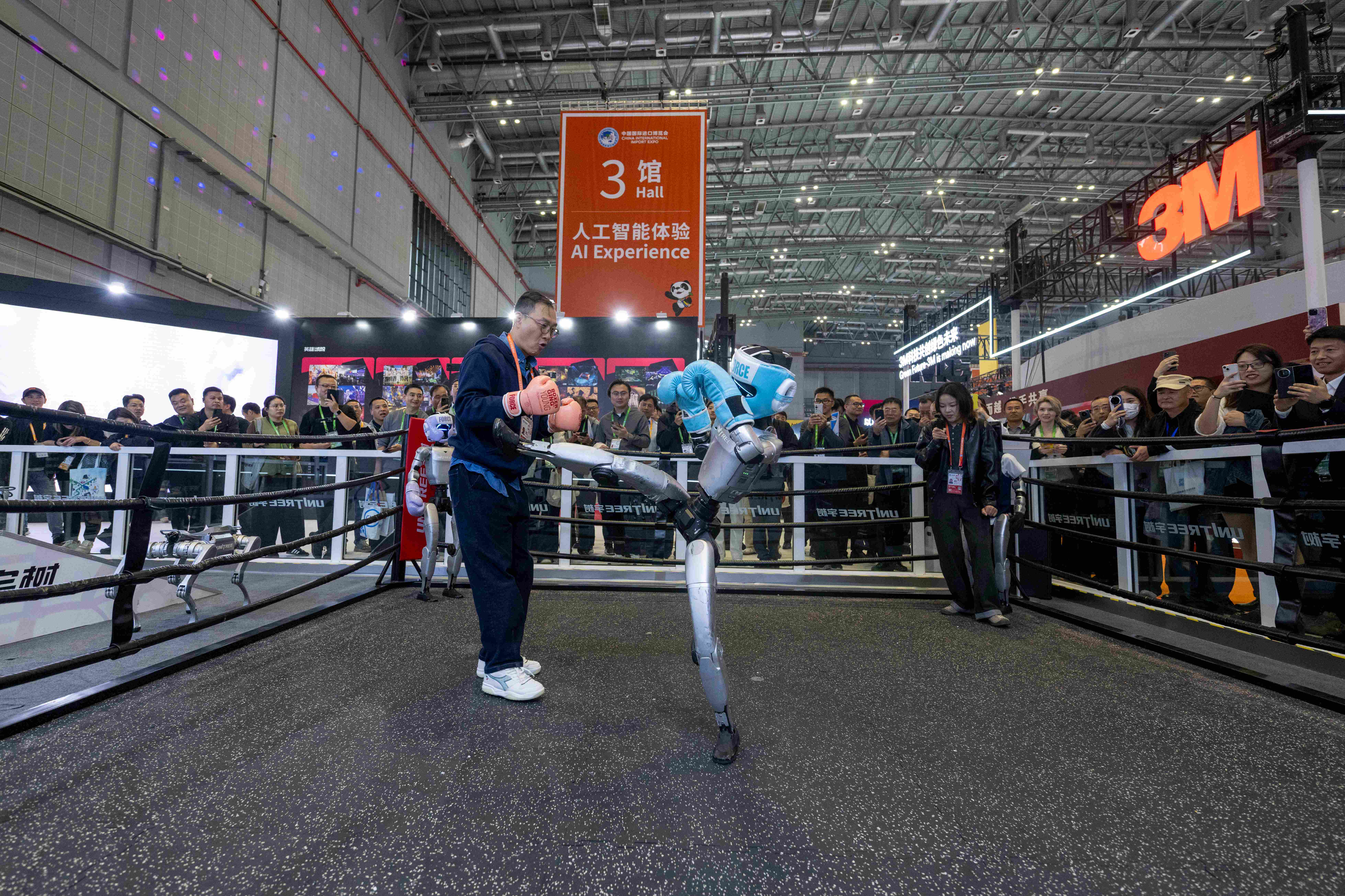在第八屆進博會技術裝備展區的宇樹科技展台,參觀者與人形機器人互動體驗格斗。人民網記者 翁奇羽攝