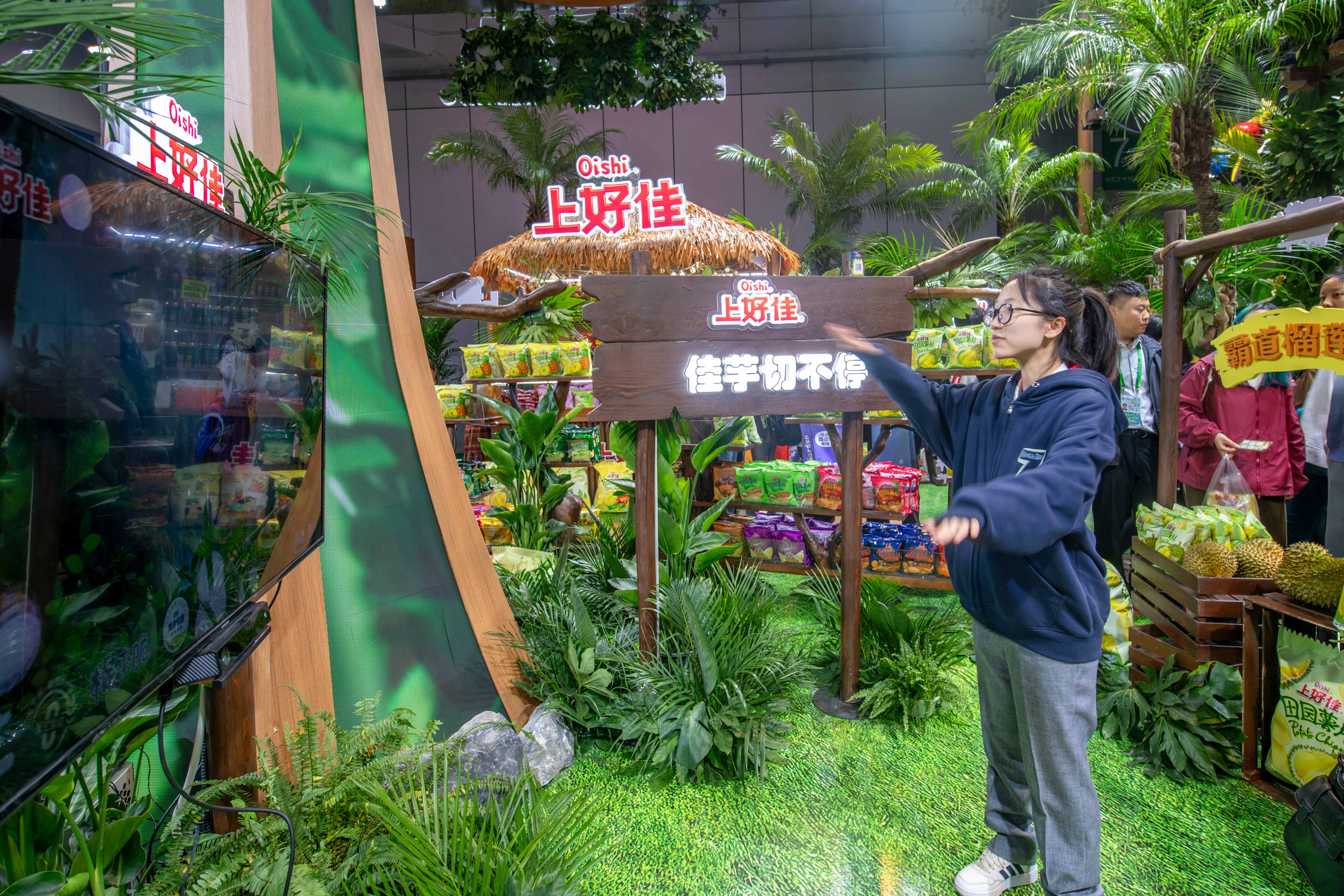 在第八届进博会农食产品展区的上好佳展台，参观者现场体验小游戏。人民网记者 翁奇羽摄