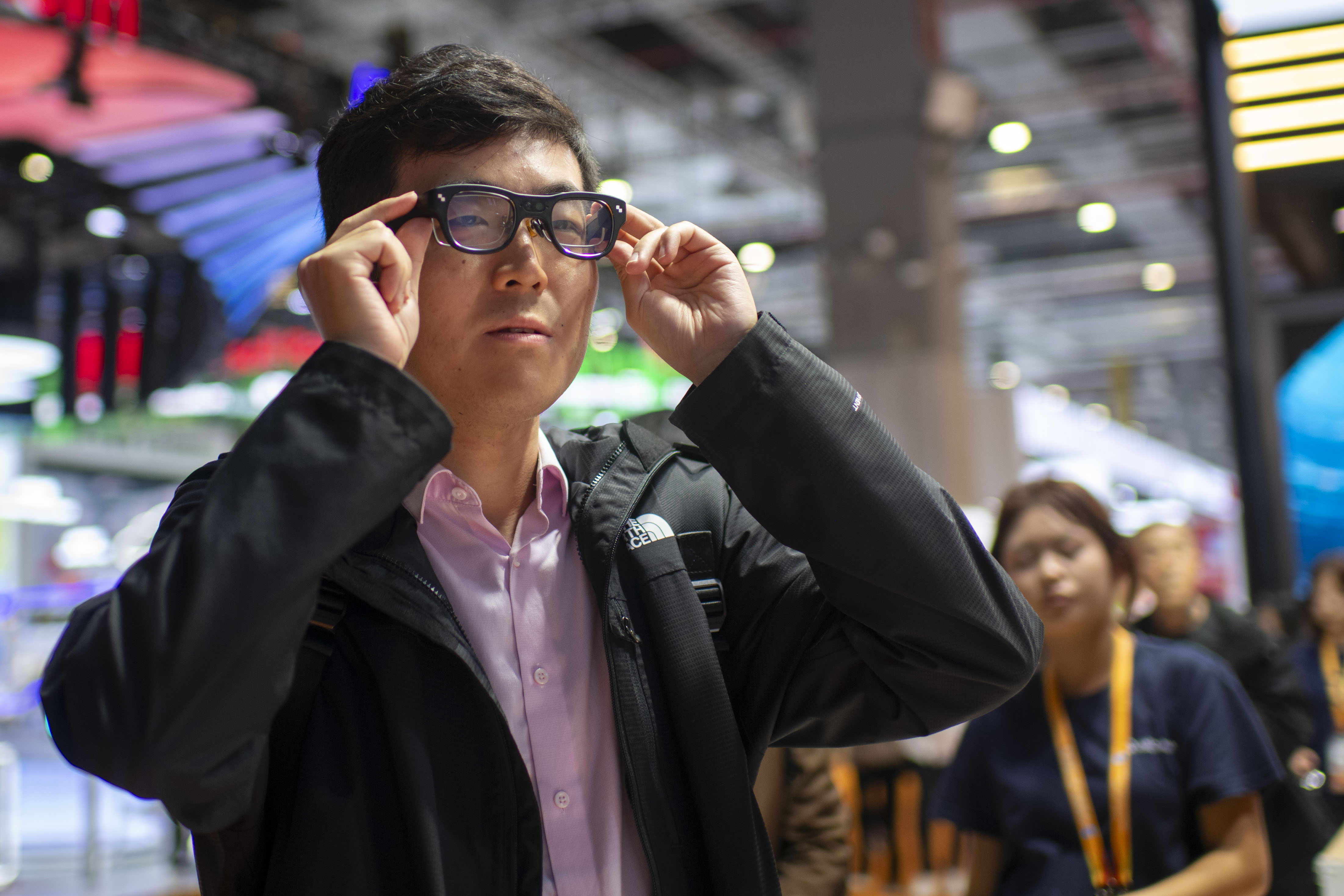 在第八届进博会技术装备展区的高通展台，参观者正在体验AI眼镜。人民网记者 翁奇羽摄