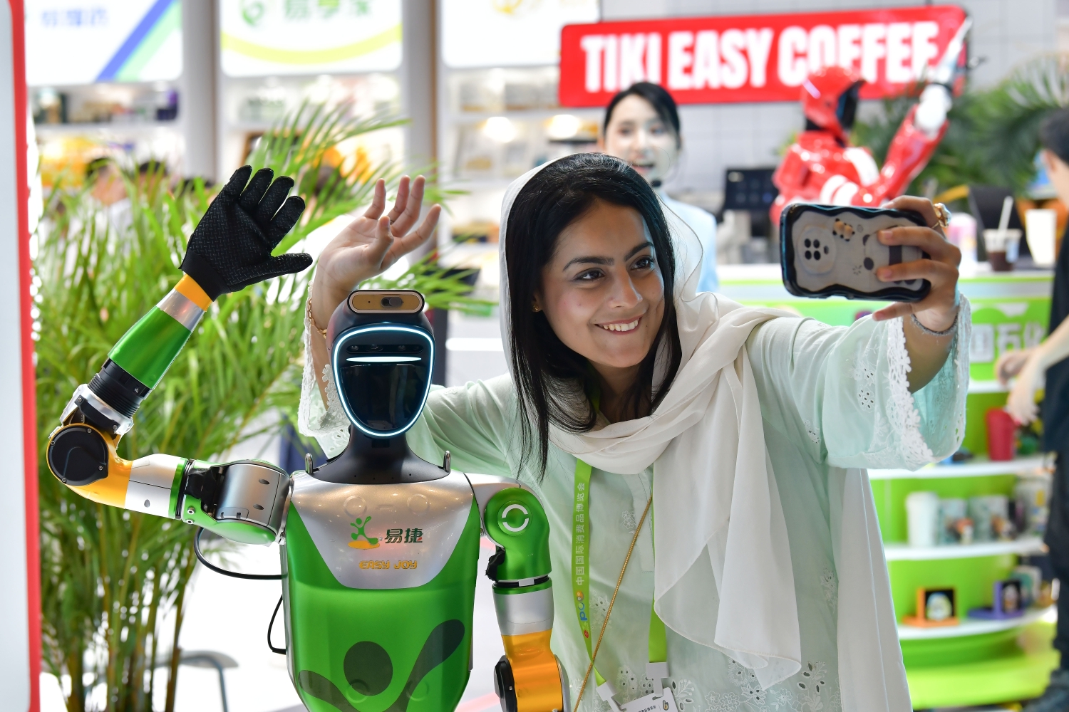 外国嘉宾与易捷机器人自拍留念，近距离体验人工智能带来的多元消费服务魅力。人民网记者 任峰涛摄