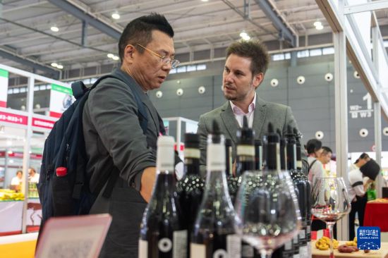 9月19日,在长沙国际会展中心,参展商(右)在介绍展出的红酒。